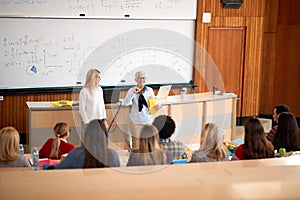 Professor helping student in class in university engaged in education