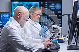 Professor and his young and professional laboratory assistant are doing scientific experiment in a modern laboratory