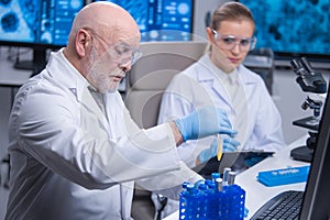 Professor and his young and professional laboratory assistant are doing scientific experiment in a modern laboratory