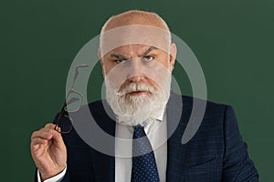 Professor or serious teacher. Elderly man teacher on a blank chalkboard during lesson, teaching class at college. Think