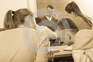 Professor watching as student write off on exams