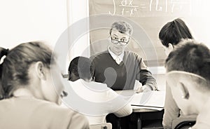 Professor watching as student write off on exams