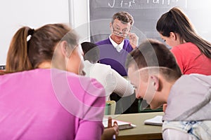 Professor watching as student write off on exams