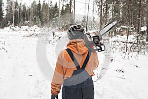 Proffesional Lumberjack hold hand saw. Winter wearing protection clothes using chainsaw. clean fallen trees