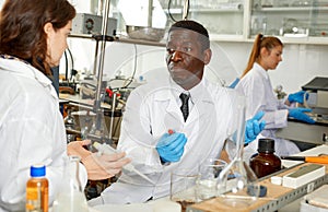 Proffesional male and female lab technicians with different test tubes