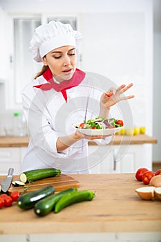 Proffesional woman cook in white uniform chopping vegetables