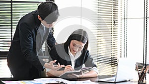 Proficient young male employee explaining a business analysis to his female colleague in office. photo