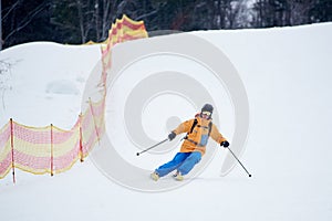 Proficient young skier concentrated on skiing down on steep ski slope. Extreme winter activities concept. Front view