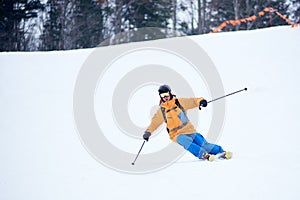 Proficient young skier concentrated on skiing down on steep ski slope. Extreme winter activities concept. Front view