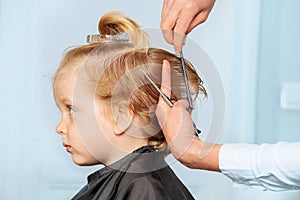 Profile of a 3 years old boy while hairstylist do haircut