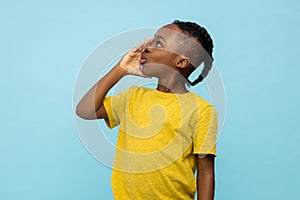 Profile of African American little boy screaming with hand near mouth