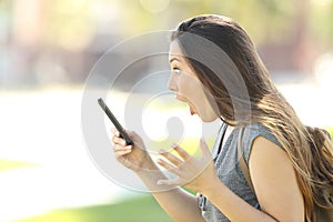 Profile of an amazed woman using a phone