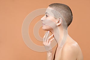 Profile of an attractive mid adult woman looking at herself in the mirror, touching her chin and pulling skin back. Skincare.