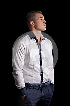 Profile of attractive young man with white shirt, hands in pockets