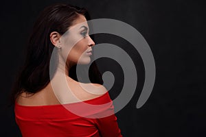 Profile of a beautiful woman in a red dress on a dark background