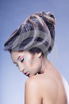 Profile Beauty portrait of an asian young woman with creative hairstyle and makeup, isolated on a blu background.