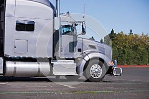 Profile of Big rig gray classic semi truck tractor going to deli