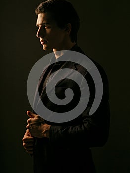 Profile of a business man dressed in black suit portrait against a dark background. Closeup portrait handsome man