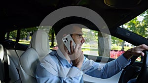 Profile of confident businessman driving electric car on urban road and talking on phone. Male businessperson operating