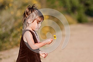 Profile of cute two-year-old girl holding flower
