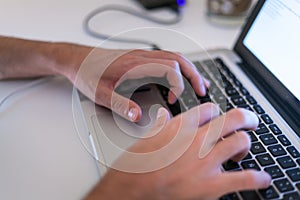 Profile detail shot of a mans dynamic hands using a laptop