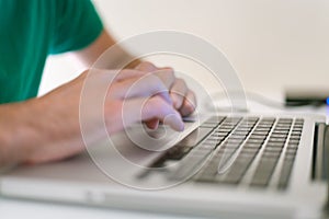 Profile detail shot of a mans dynamic hands using a laptop on a whitetable