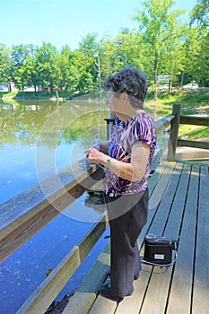 Older woman views pond with portable oxygen tube photo