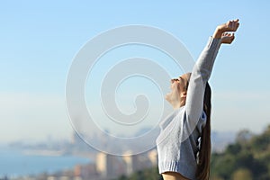 Profile of excited woman raising arms in city outskirts photo