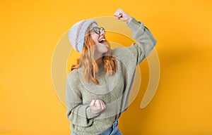 Profile of excited young girl with closed eyes and clenched fists, isolated on yellow background. Yes concept. Good news. Pretty