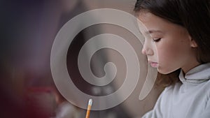 Profile of the face of a girl who looks carefully and writes with a pencil. Modern online learning. A child looks at the