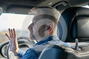 Profile of a friendly car driver with graying hair and beard taken from inside the car