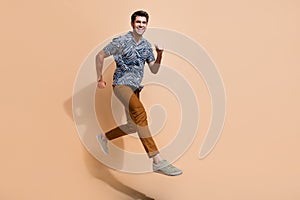 Profile full body photo of energetic motivated young man workaholic running to get promotion in career islated on beige