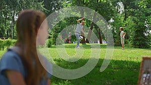 Profile girl watching soccer game in park. Father play football with son.