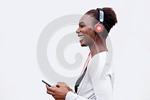 Profile of happy young black woman listening to music with smart phone and headphones