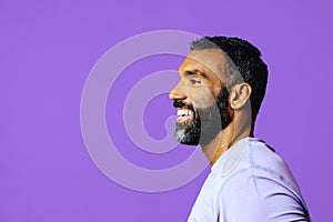 profile headshot of a handsome smiling african american man with beard and mustache purple shirt looking away at copy