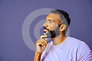 profile headshot of a handsome smiling african american man with beard and mustache purple shirt looking away at copy