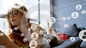 Profile icons connecting with lines over caucaisan young woman using tablet pc while lying on sofa