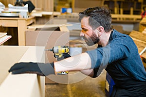 Profile of a latin man working with a power drill in a woodshop photo