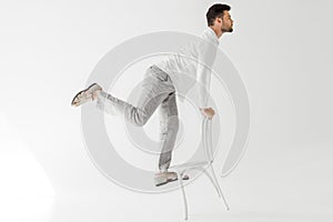 profile of male model in linen clothes balancing on chair