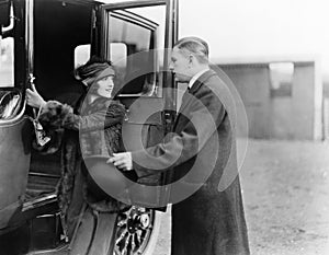 Profile of a man helping a young woman board a car