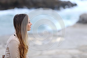 Profile of a pensive woman on the beach in winter