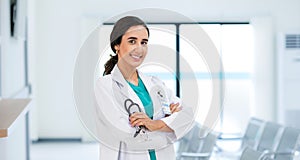 A profile photo of an attractive smiling female doctor wearing a white medical gown and holding a stethoscope, standing in the