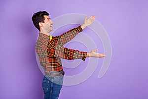 Profile photo of funny amazed guy stretch hands look empty space wear bow tie plaid shirt isolated violet background