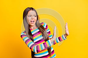 Profile photo of little disgusted girl raise two arms show denial wear striped shirt isolated yellow color background