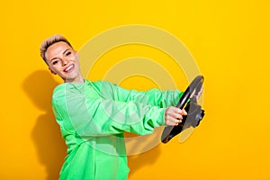 Profile photo of pretty positive girl toothy smile hands hold wheel isolated on yellow color background