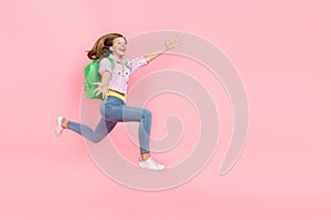 Profile photo of surprised funky lady jump catch empty space wear backpack jacket isolated pink color background