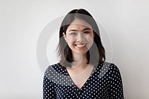 Headshot portrait of smiling asian woman isolated on grey wall photo