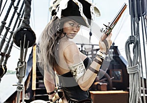 Profile of a Pirate female captain standing on the deck of her ship with pistol in hand.