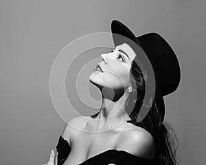 Profile portrait of a beautiful lady wearing a black hat and looks up