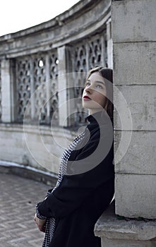 Profile portrait of the beautiful red-haired girl looking up, standing near old building. Outside portrait.